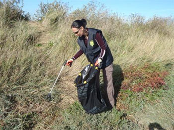 A person collecting litter from a beach