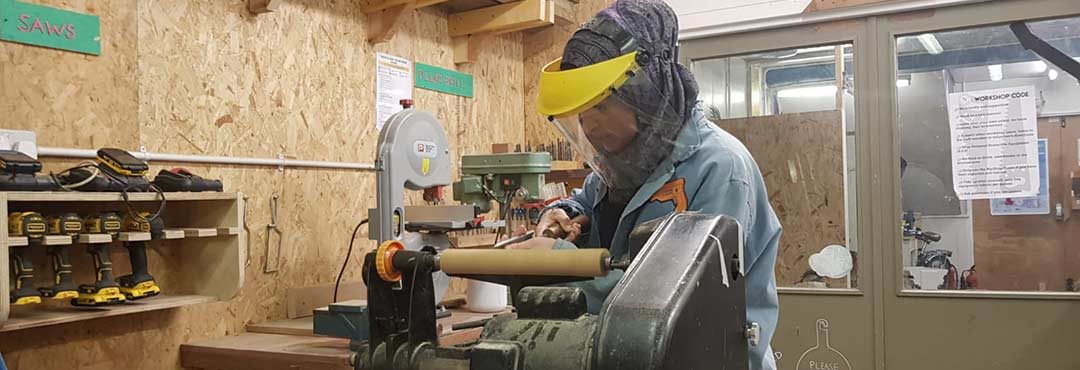 Woman working on a lathe as part of the Building Roots project