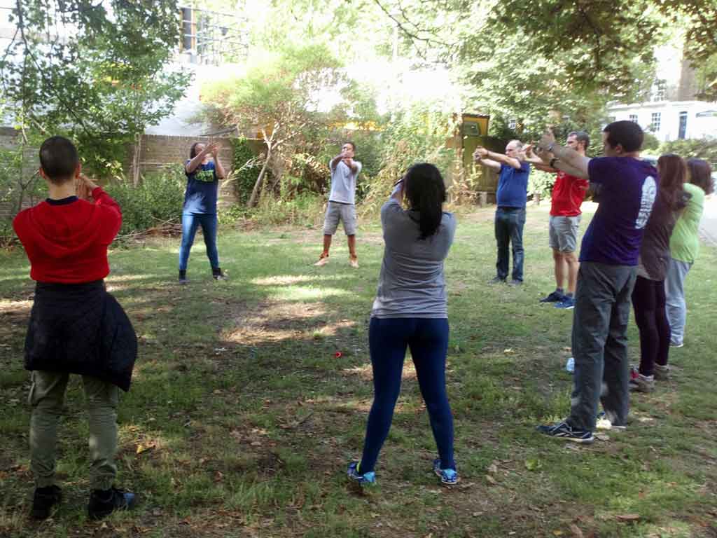 A group of people in the outdoors completing a warm up for a TCV Green Gym