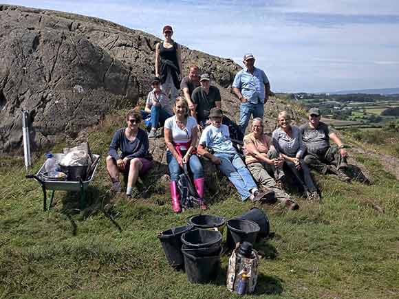 Volunteers taking a break on a hillside logo