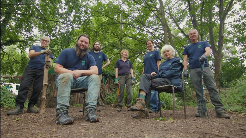 Groupf of TCV volunteers looking at the camera, sat in a woodland