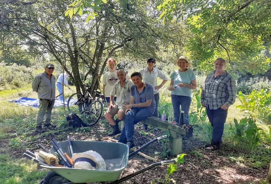 Mixed group of green space volunteers with wheelbarrow and tools