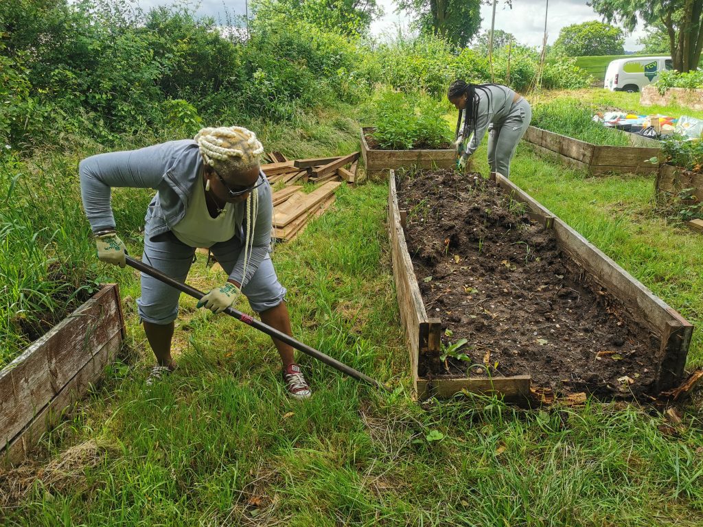 2 black women mending a raised bed planter