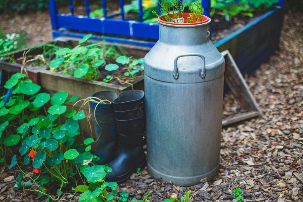 Wellington boots, plant boxes and a silver-coloured vessel on wood chippings