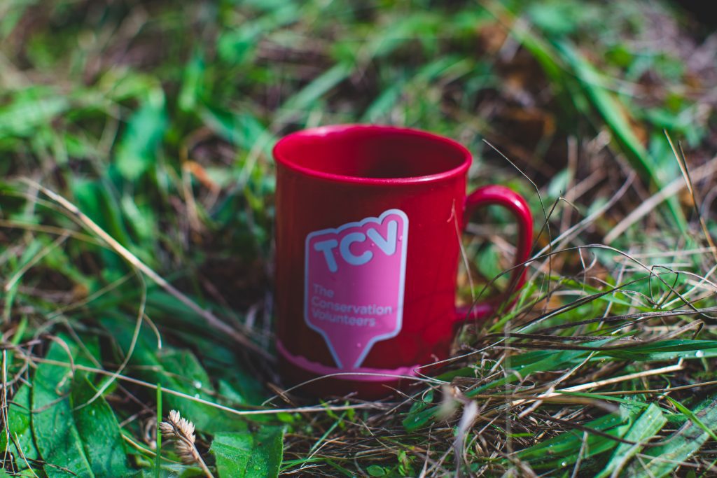 Red cup with TCV logo sat in grass