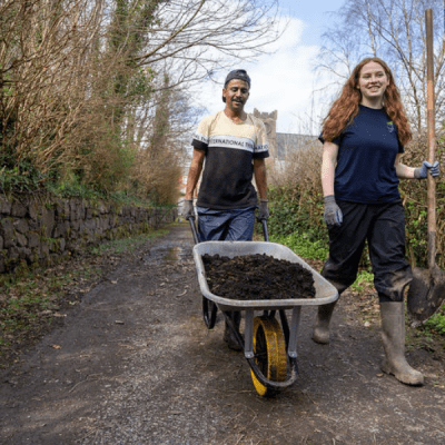 TCV volunteers transport compost in wheelbarrow