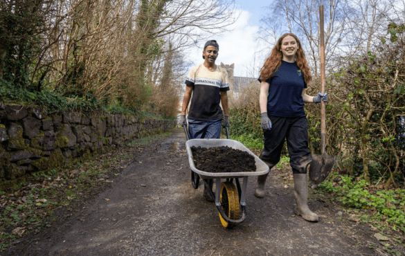 TCV volunteers transport compost in wheelbarrow