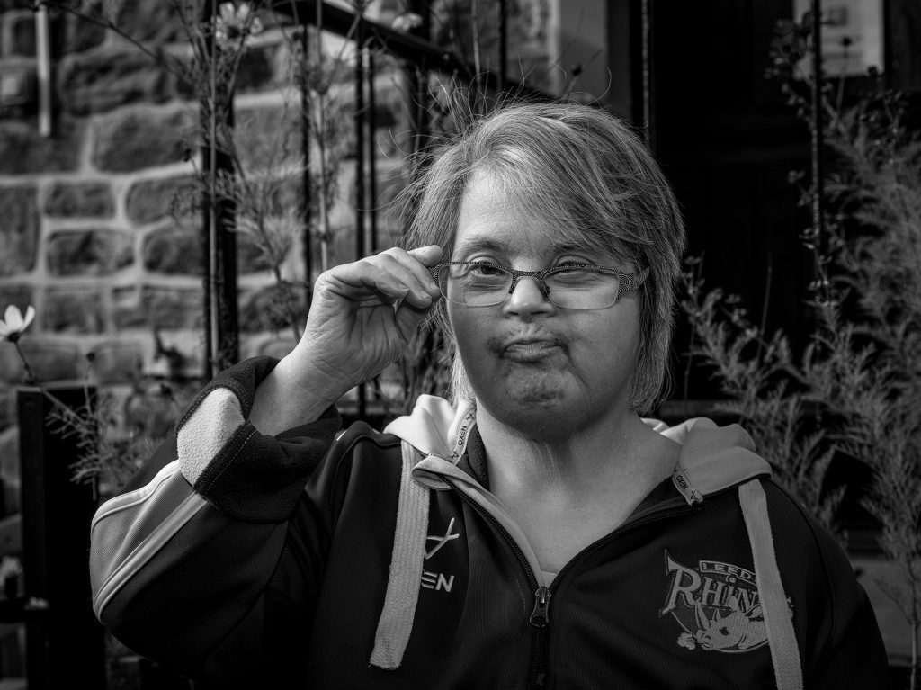 Black and white portrait image of a lady with down syndrome wearing glasses. Credit Mark Slater, TCV