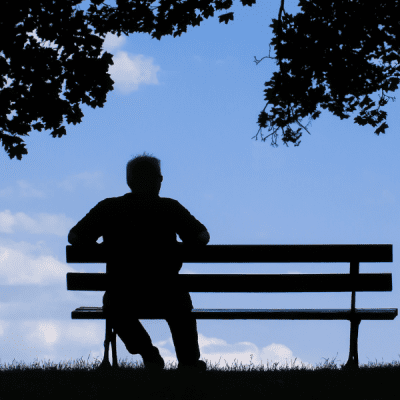 TCV Combatting Loneliness Together - a person sits on bench in park under a tree