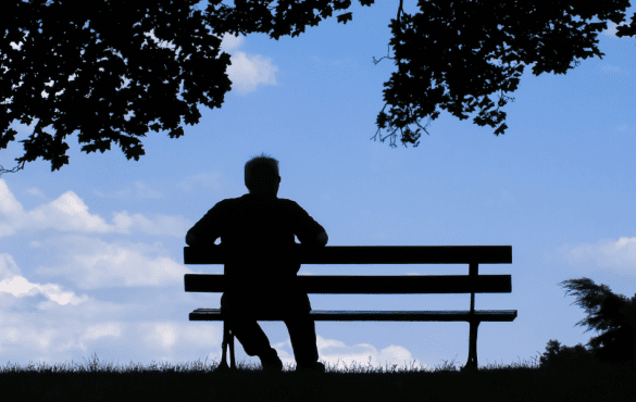 TCV Combatting Loneliness Together - a person sits on bench in park under a tree