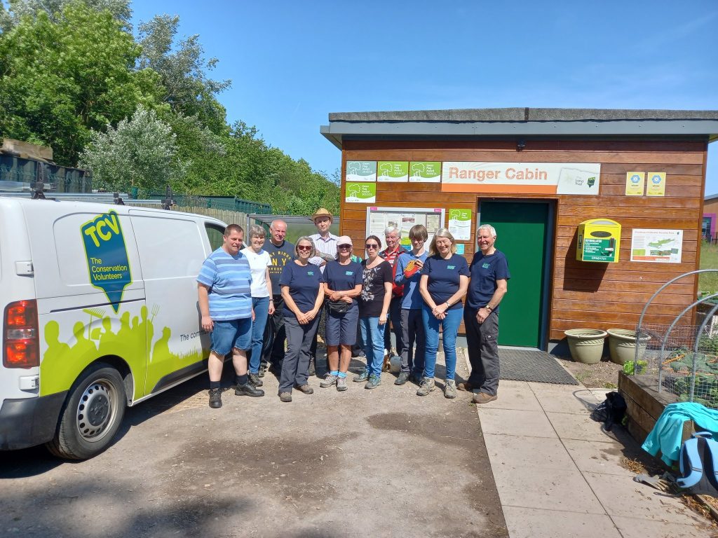 Group of volunteers outside a cabin with a van that has a TCV logo