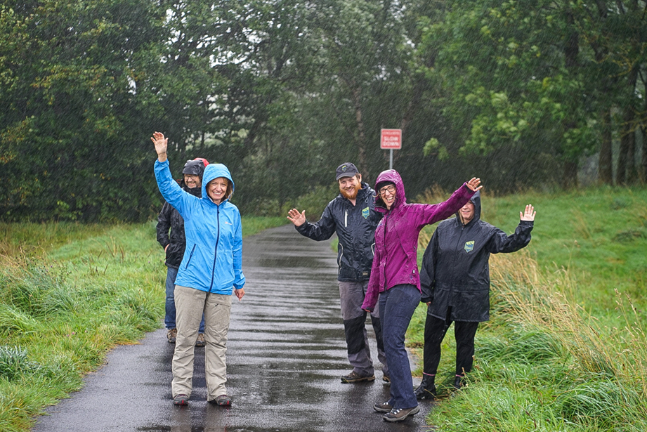 Group of people in the rain stood on a path leading to woodland