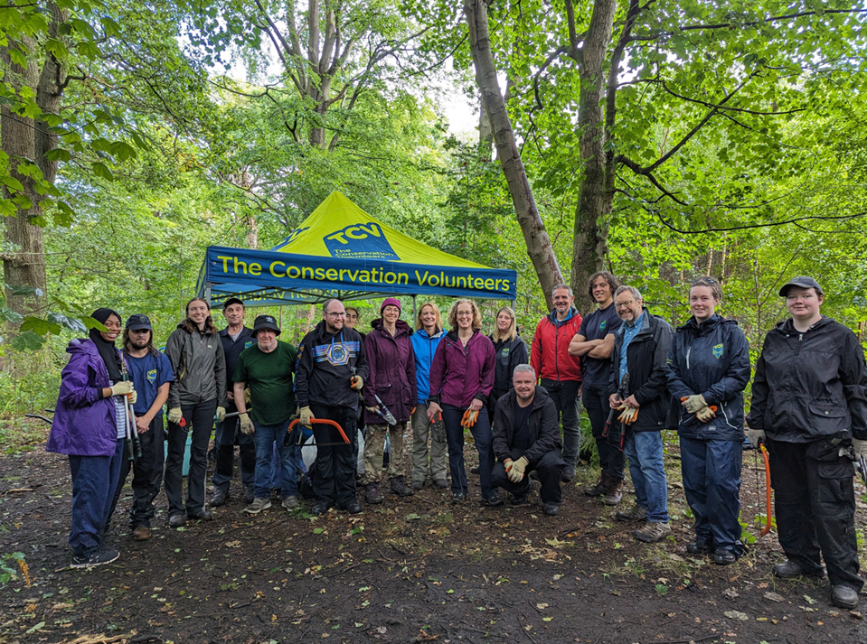 Group of people in woodland with The Conservation Volunteers marquee