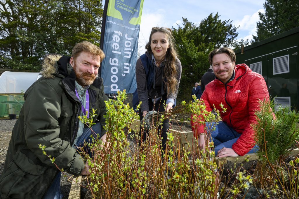 Group of people planting trees and smiling at camera