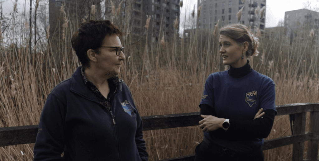 Two people talking in an ecology park with an urban background