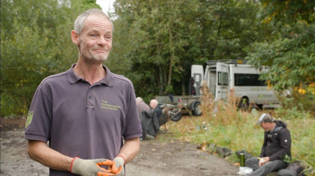 Eric Joinson from The Conservation Volunteers in a woodland with a van in the background.
