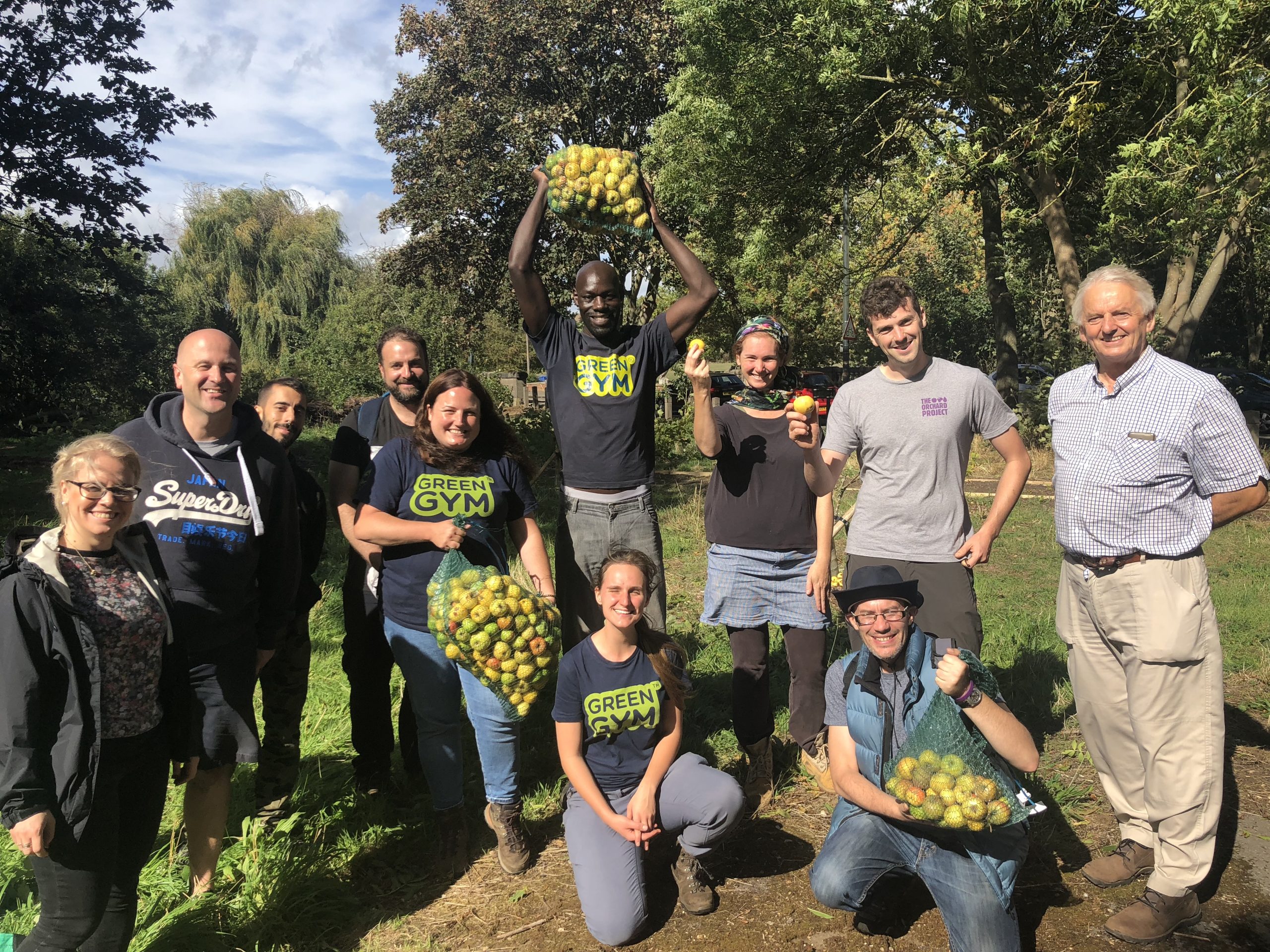Group of people in TCV Green Gym t-shirts holding apples from a harvest