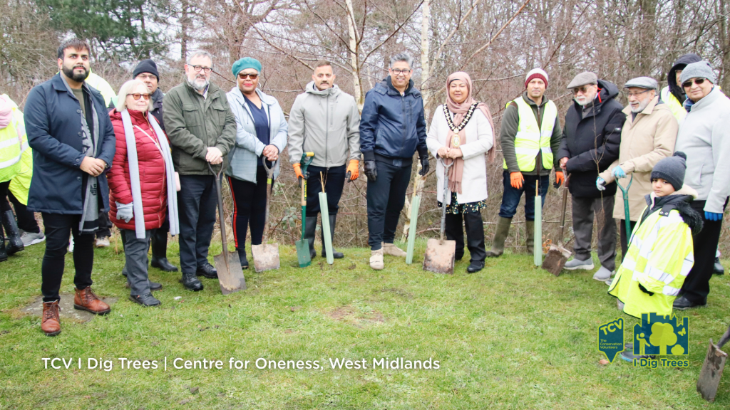 A diverse group of people stand together in the West Midlands of the UK, ready to plant their free trees from I Dig Trees, smiling and enjoying the outdoors.