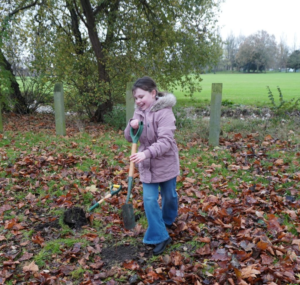 Smiling child with a spade planting a tree with TCV 