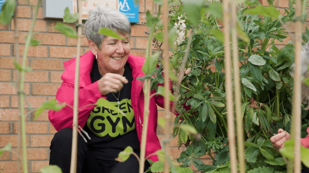 A TCV volunteer smiles as she attends to a vegetable garden.